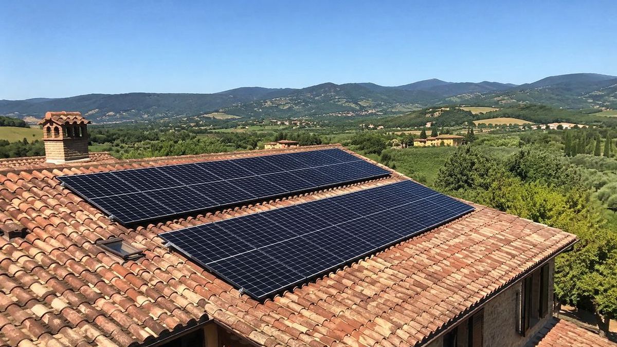 Pannelli fotovoltaici sul tetto con coppi di una villa italiana sotto cielo azzurro